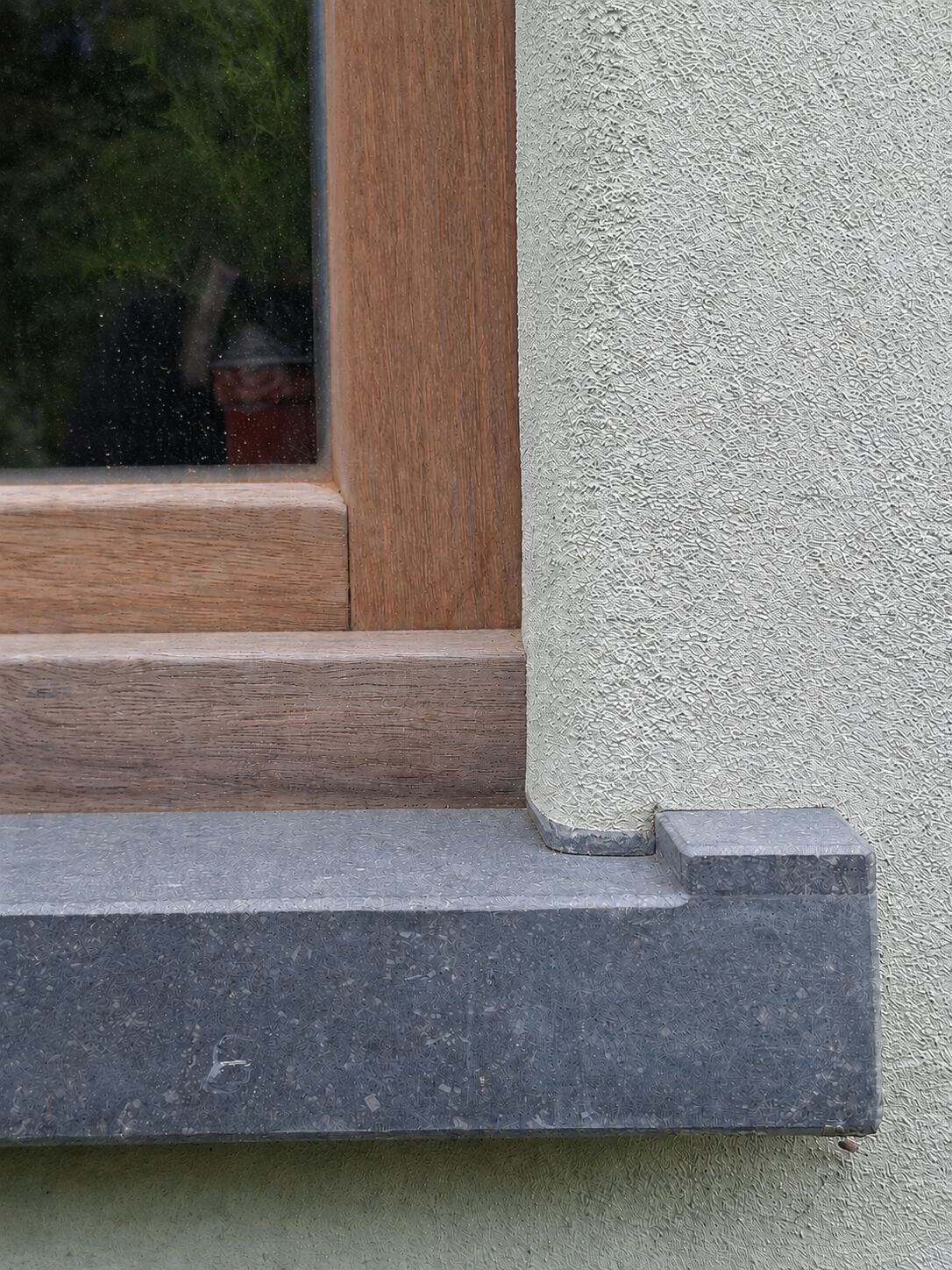 Houten raamomlijsting met vensterbank tegen gevel afgewerkt met kalkpleister